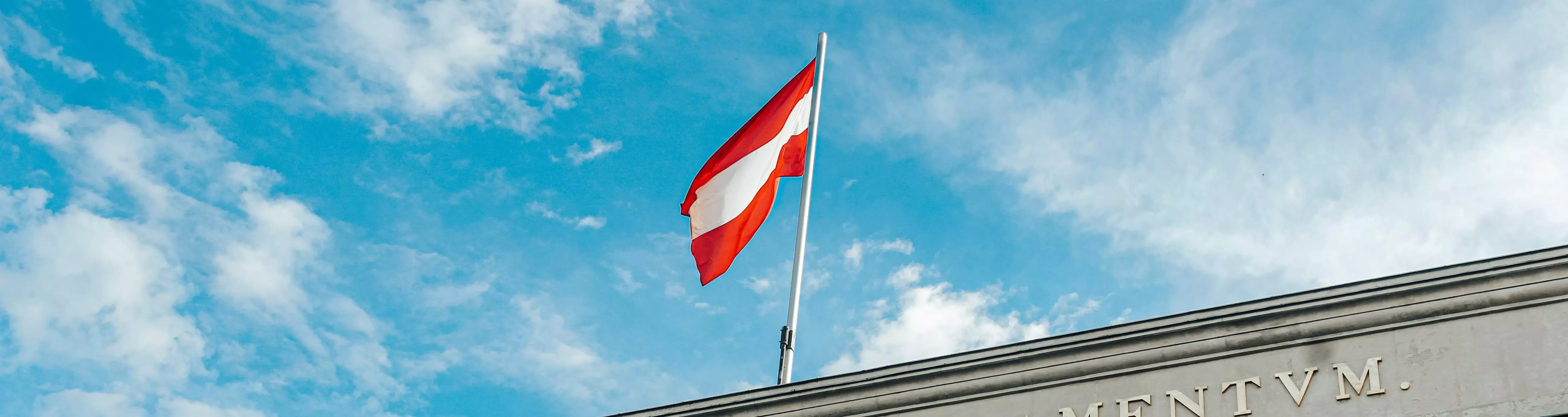 Österreichische Flagge über Parlament vor blauen Himmel mit Wolken